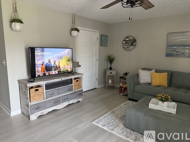 A living room with a television on a stand and a couch.