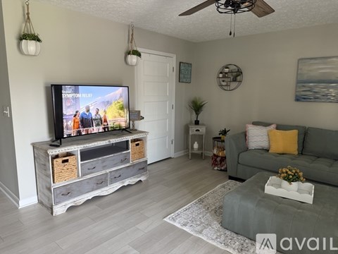 A living room with a television on a stand and a couch.