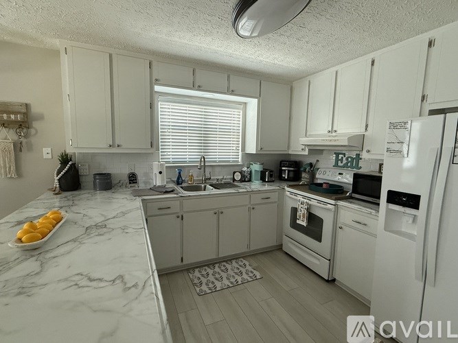 A kitchen with white cabinets and a white fridge.