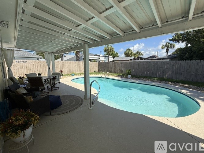 A pool in a backyard with a patio and a white awning.