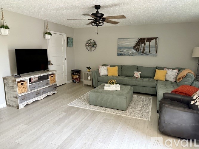 A living room with a green couch and a wooden entertainment center.