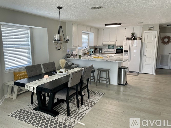 A kitchen with a dining table and chairs in the foreground.