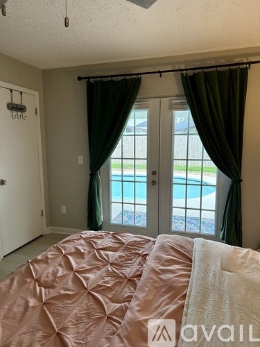 A bedroom with a bed and a pool visible through the window.