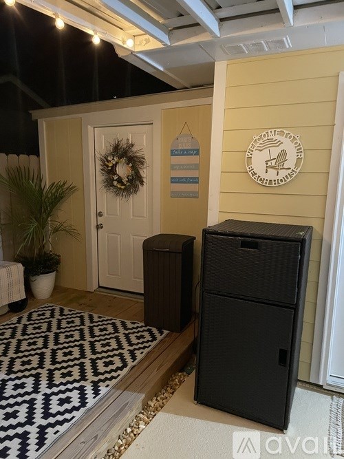 A black speaker stands on a rug in front of a yellow wall.