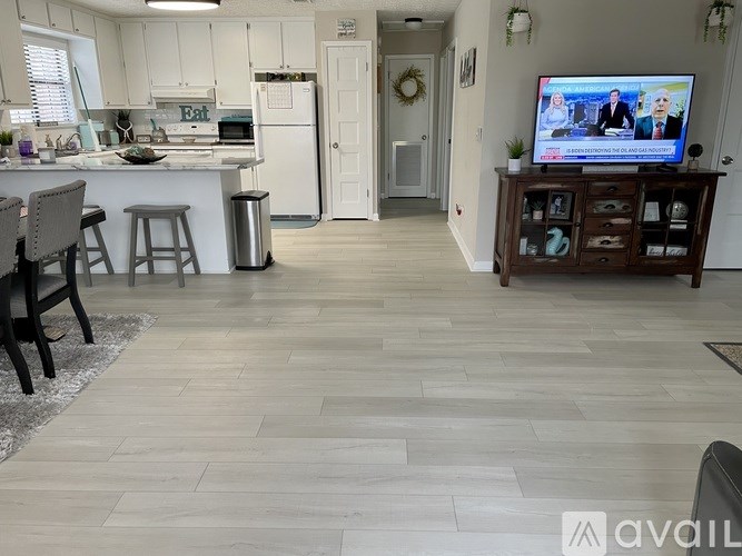 A kitchen with a TV on a stand and a doorway leading to another room.