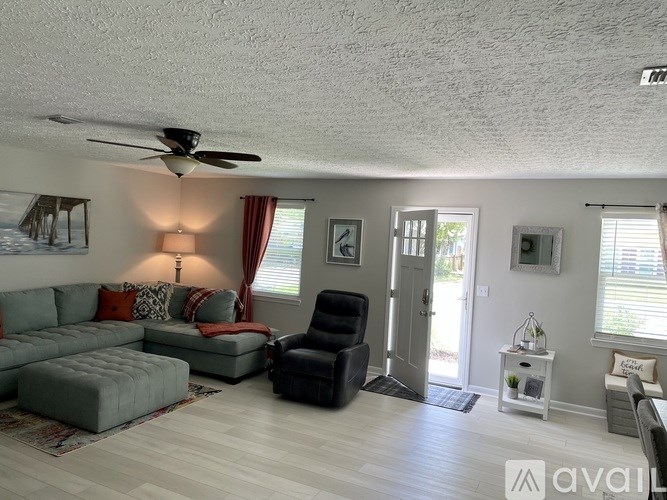 A living room with a grey couch, a black chair, and a ceiling fan.
