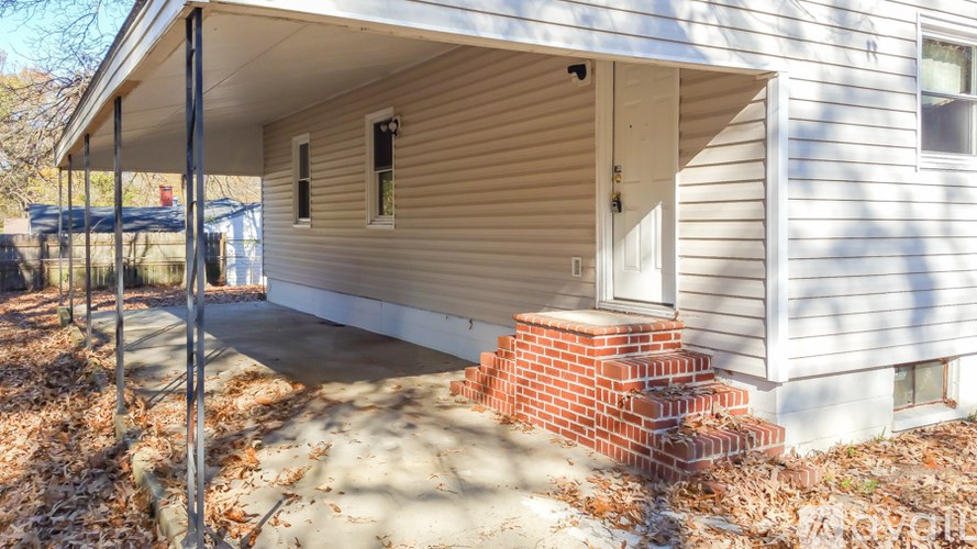 A house with a white siding and a red brick staircase leading to the front door.