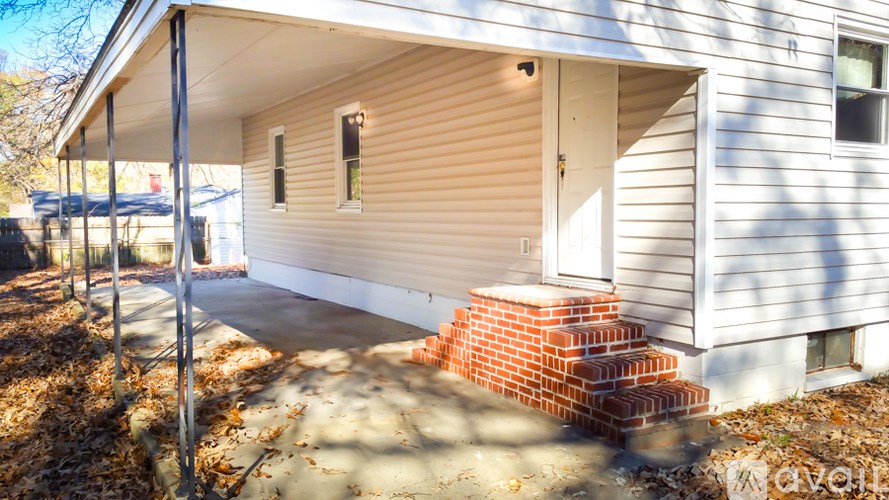 A house with a white siding and a brown brick staircase leading to the door.