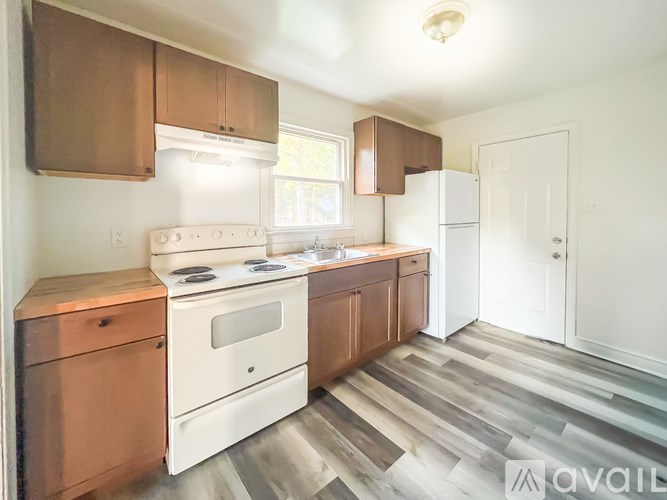 A kitchen with a white stove top oven and wooden cabinets.