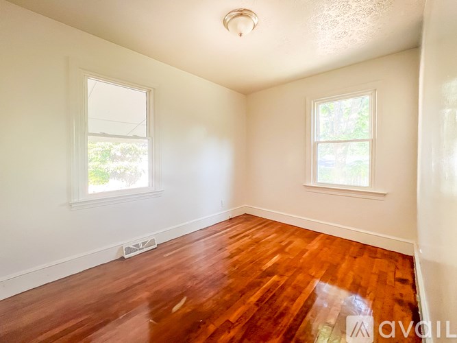 A room with wooden floors and two windows.