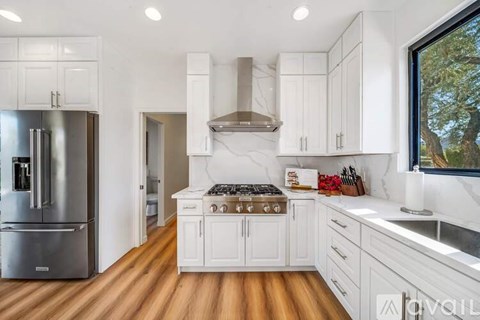 A modern kitchen with white cabinets and a wooden floor.