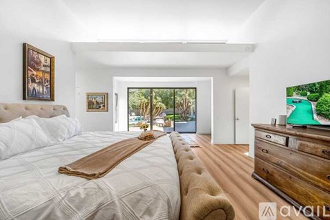 A bedroom with a large bed and a wooden dresser.