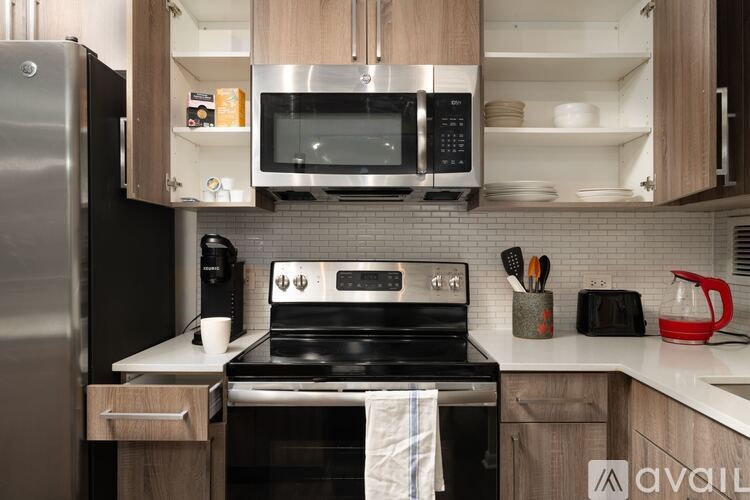 A modern kitchen with a stainless steel refrigerator, microwave, and oven.
