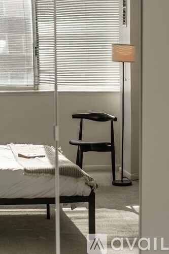 A bed with a white blanket and a chair in front of a window.
