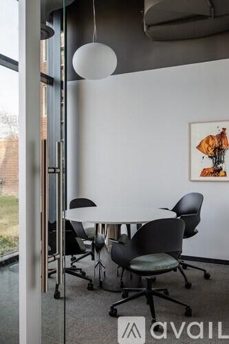 A conference room with a table, chairs and a painting on the wall.