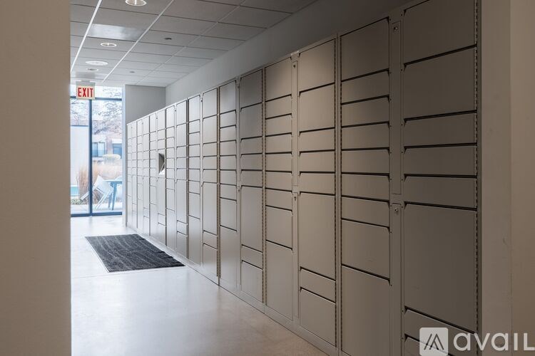 A long hallway with a row of lockers on the side and an exit sign above.