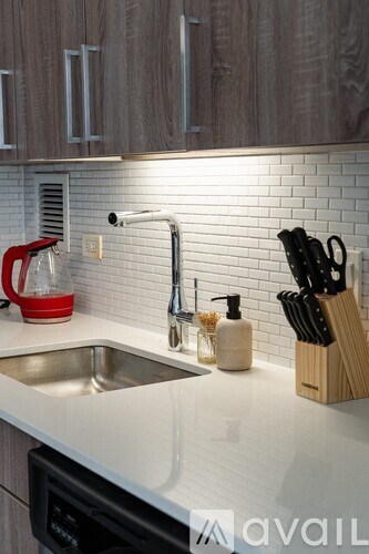 A kitchen with a sink and a red kettle on the counter.