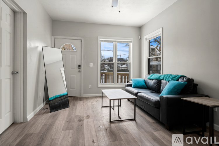 A room with a black couch and a whiteboard leaning against the wall.