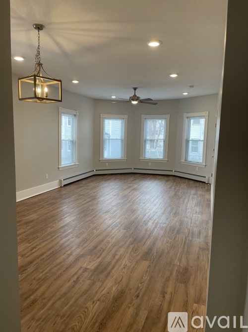 A room with wooden flooring and a chandelier hanging from the ceiling.
