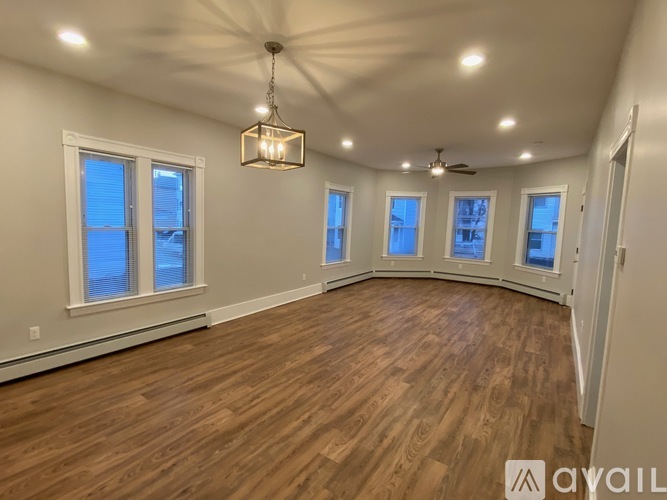 A spacious room with wooden flooring and a ceiling fan.