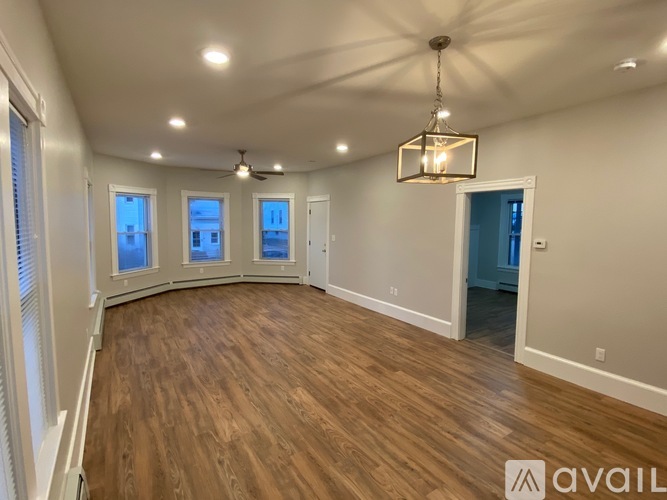 A spacious room with wooden flooring and a chandelier hanging from the ceiling.