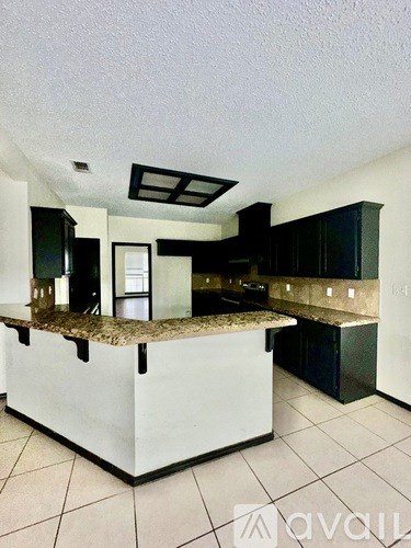 A kitchen with a granite countertop and black cabinets.