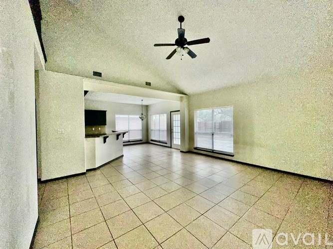 A spacious room with a ceiling fan and large windows.