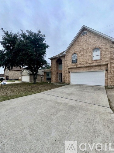 A house with a garage and a tree in front of it.