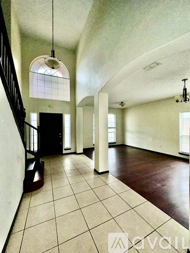 A spacious room with a staircase and a chandelier.