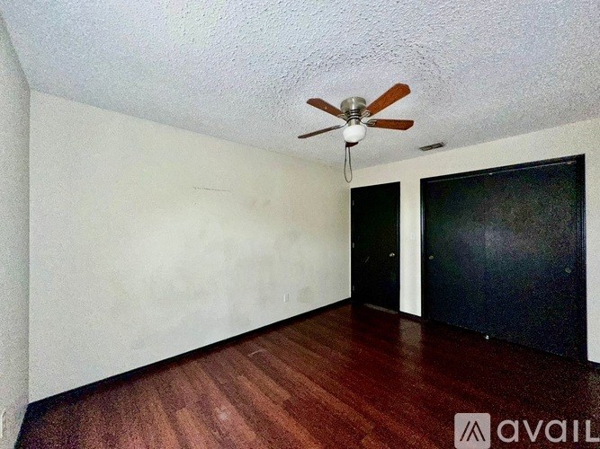 A room with a ceiling fan and wooden flooring.
