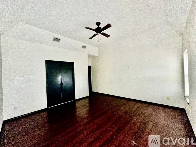 A room with a ceiling fan and a black door.