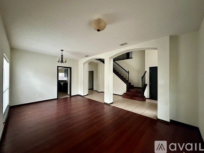 A spacious living room with hardwood floors and a staircase leading to another level.