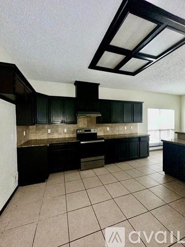 A kitchen with black cabinets and a tiled floor.