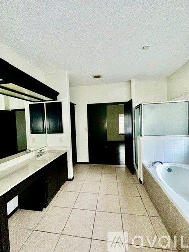 A bathroom with a white tub and black cabinets.