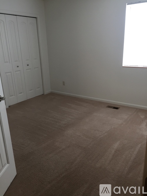 A room with a carpeted floor and a white door.