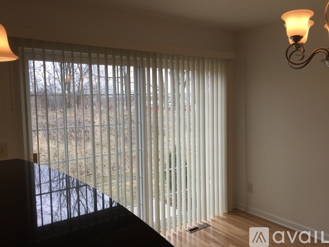 A room with a large window covered by white blinds.