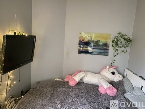 A plush unicorn toy is lying on a bed in a bedroom.