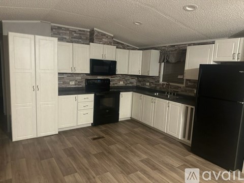 A kitchen with black appliances and white cabinets.
