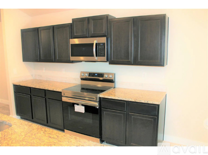 A kitchen with black cabinets and a granite countertop.