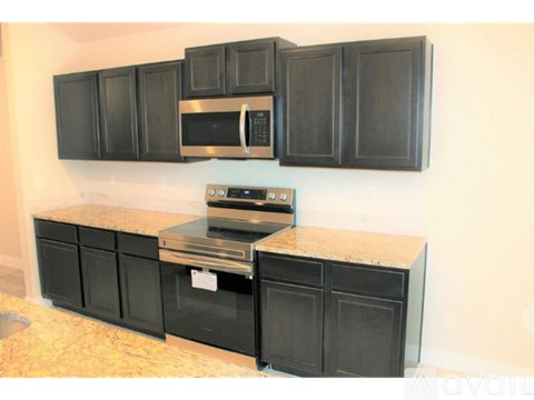 A kitchen with black cabinets and a granite countertop.
