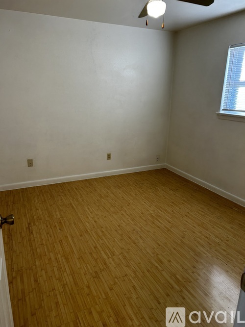 A room with wooden flooring and a window with blinds.