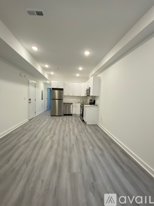 A long, empty hallway with a kitchen area at the end.