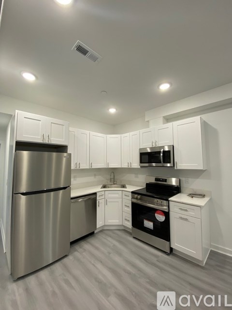 A kitchen with white cabinets and a stainless steel refrigerator.