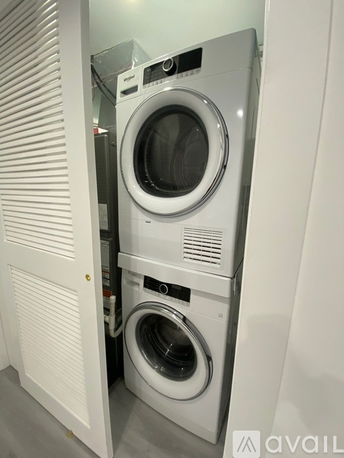 A white washing machine is tucked into a white cabinet.
