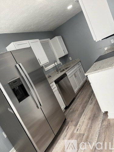 A kitchen with a stainless steel refrigerator and white cabinets.