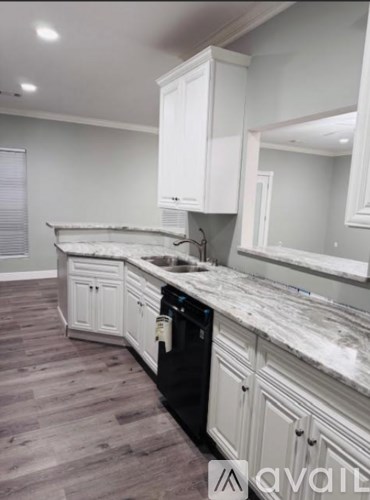 A kitchen with white cabinets and a black dishwasher.