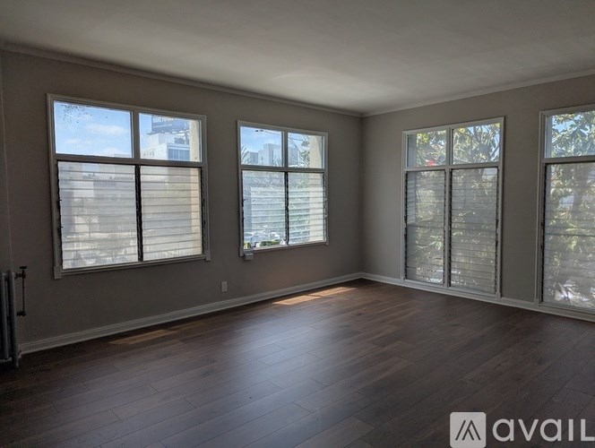 A room with wooden floors and three windows.