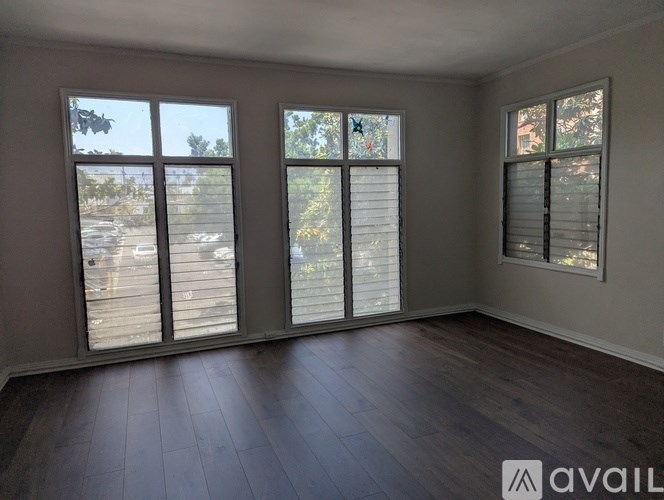 A room with wooden floors and three windows.
