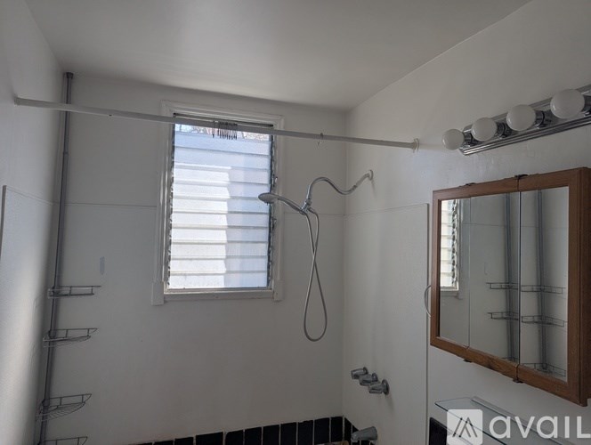 A bathroom with a window and a mirror on the wall.