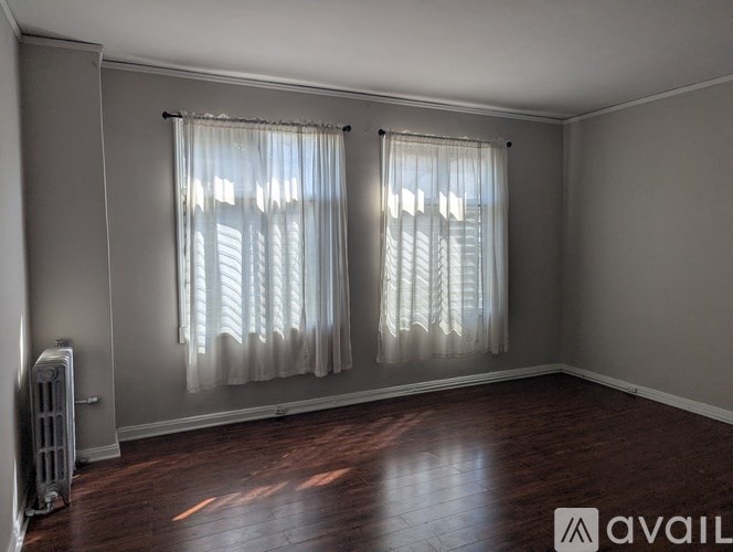A room with wooden floors and a window with curtains.